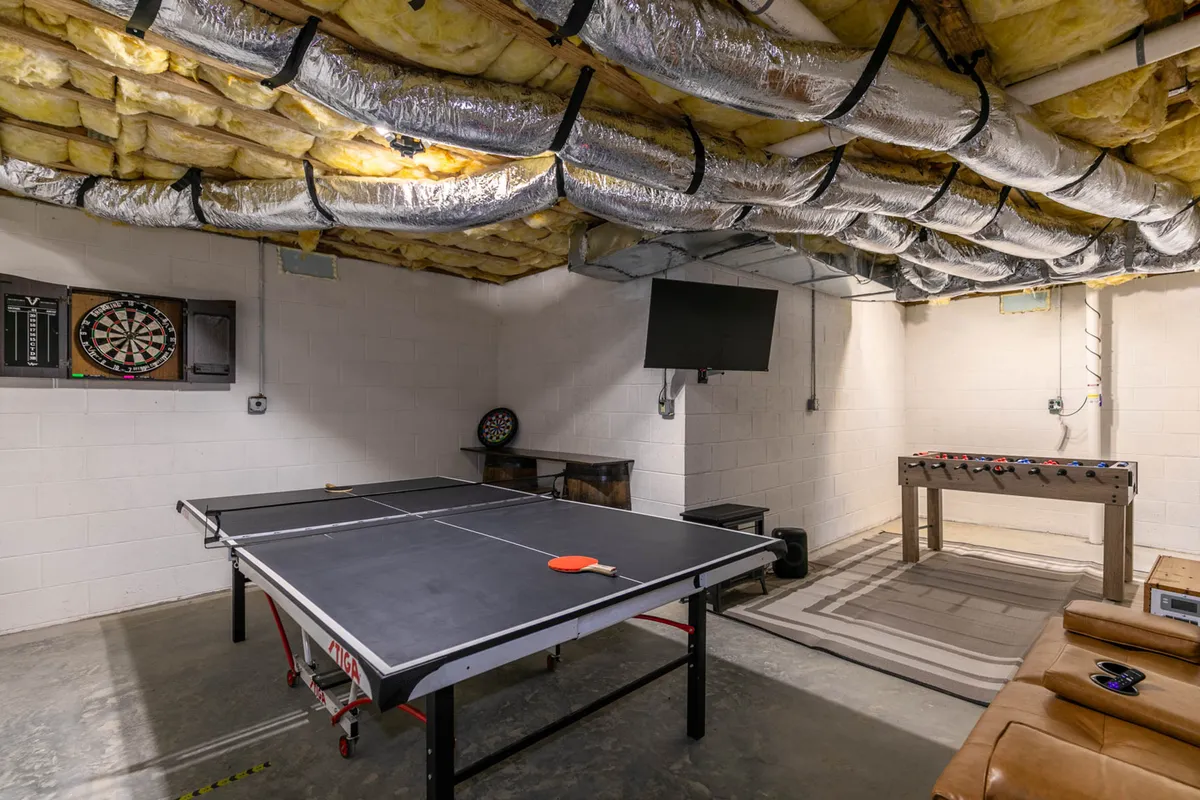 A vibrant game room featuring a ping pong table, foosball table, dartboard, and a TV. The space is bright and inviting, with enough room for group activities and tournaments, and the variety of games caters to players of all ages.