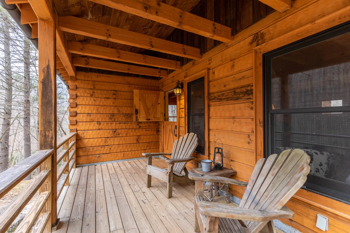 A tranquil outdoor seating area with wooden chairs and a table, accented by a lantern and positioned near the cabin’s entrance door. The setup is ideal for sharing meals, drinks, or heartfelt conversations while surrounded by serene mountain scenery.